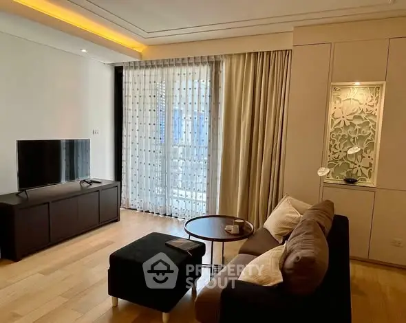 Modern living room with stylish decor and natural light, featuring a cozy sofa and entertainment unit.