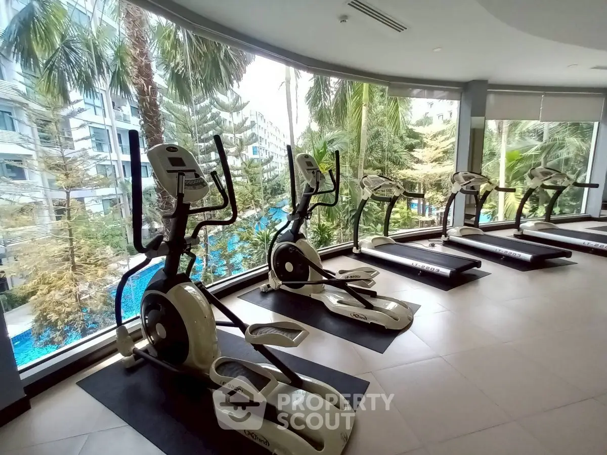 Modern gym with elliptical machines and poolside view in luxury condo