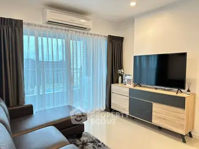 Modern living room with sleek furniture and large TV, featuring a balcony view.