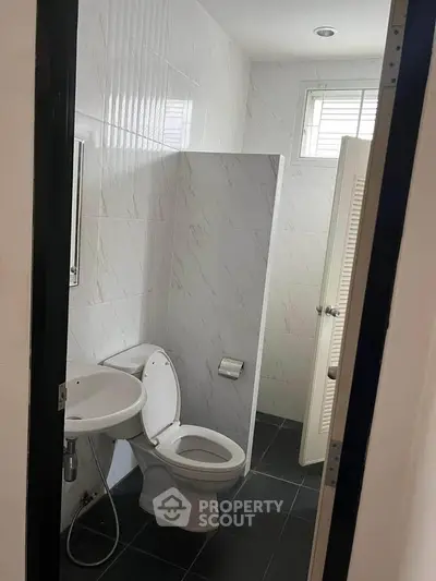 Compact bathroom with modern fixtures and tiled walls, featuring a toilet and sink.
