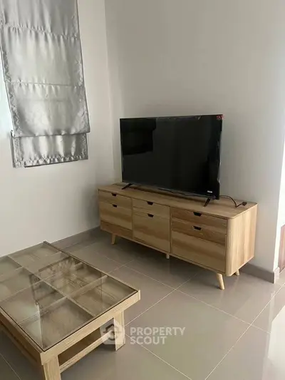 Modern living room with sleek TV stand and glass coffee table on tiled floor.