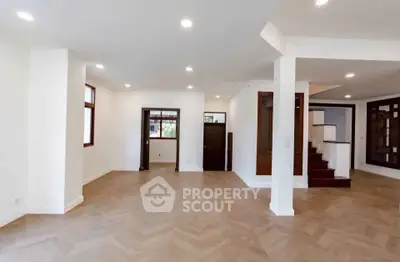 Spacious open-plan living room with elegant wooden flooring and modern lighting.