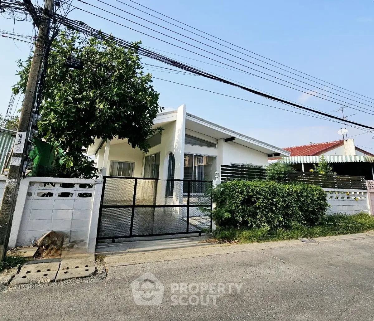 Charming single-story house with lush greenery and gated entrance in a serene neighborhood.
