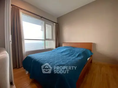 Cozy bedroom with large window and blue bedding, offering serene natural light.