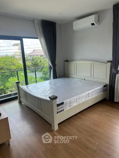 Spacious bedroom with large window and balcony access, featuring modern air conditioning and elegant wooden flooring.