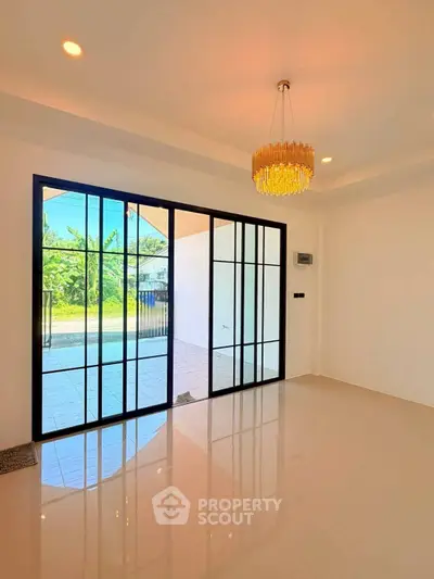 Elegant interior with modern chandelier and large glass doors opening to a patio.