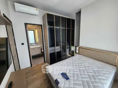 Modern bedroom with sleek wardrobe and air conditioning, featuring a cozy bed and stylish bathroom access.