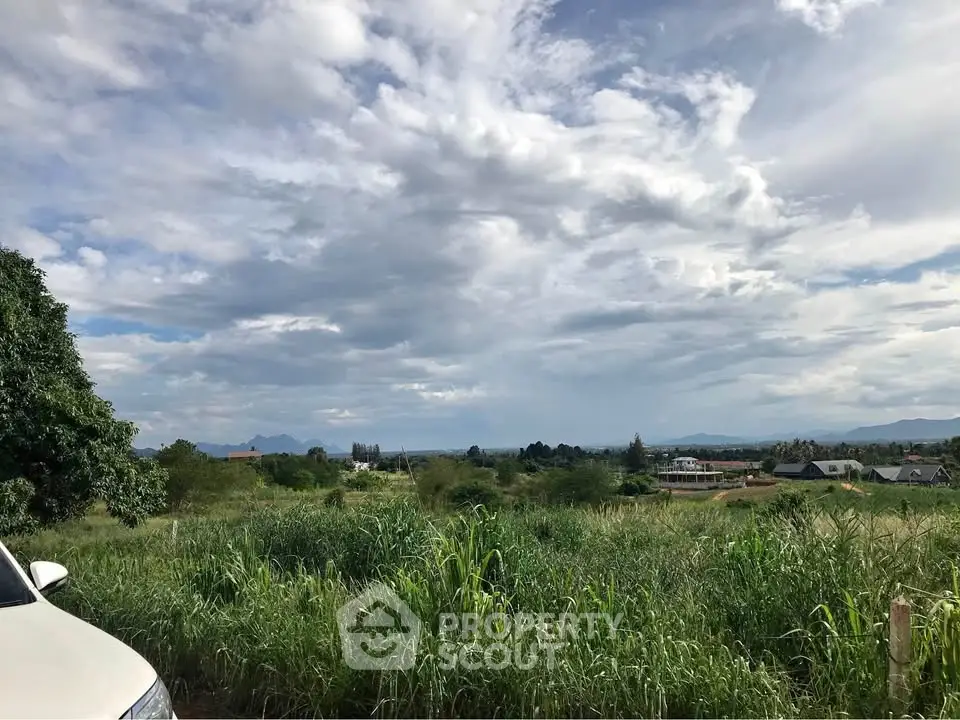Expansive land with lush greenery and distant mountain views, perfect for development.
