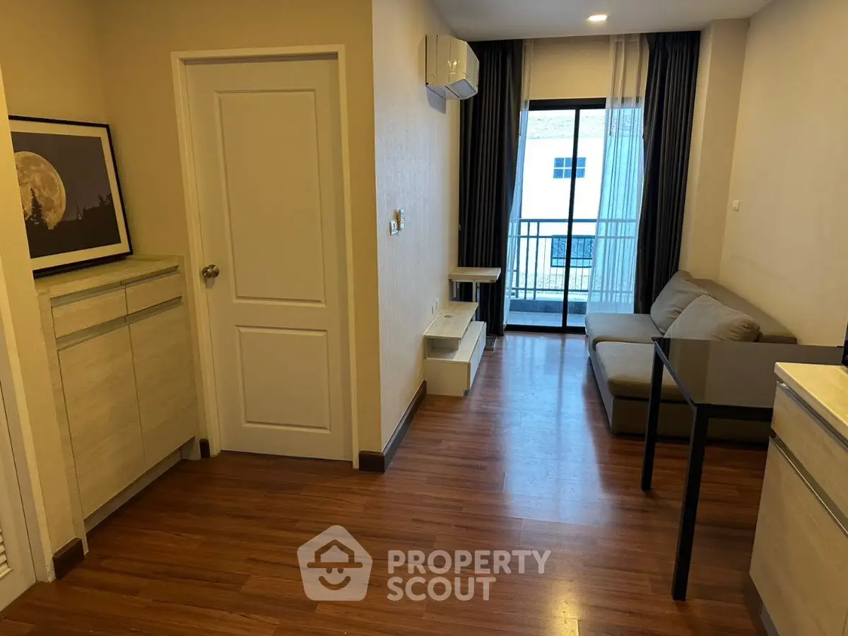 Modern living room with wooden flooring, cozy sofa, and balcony access in a stylish apartment.
