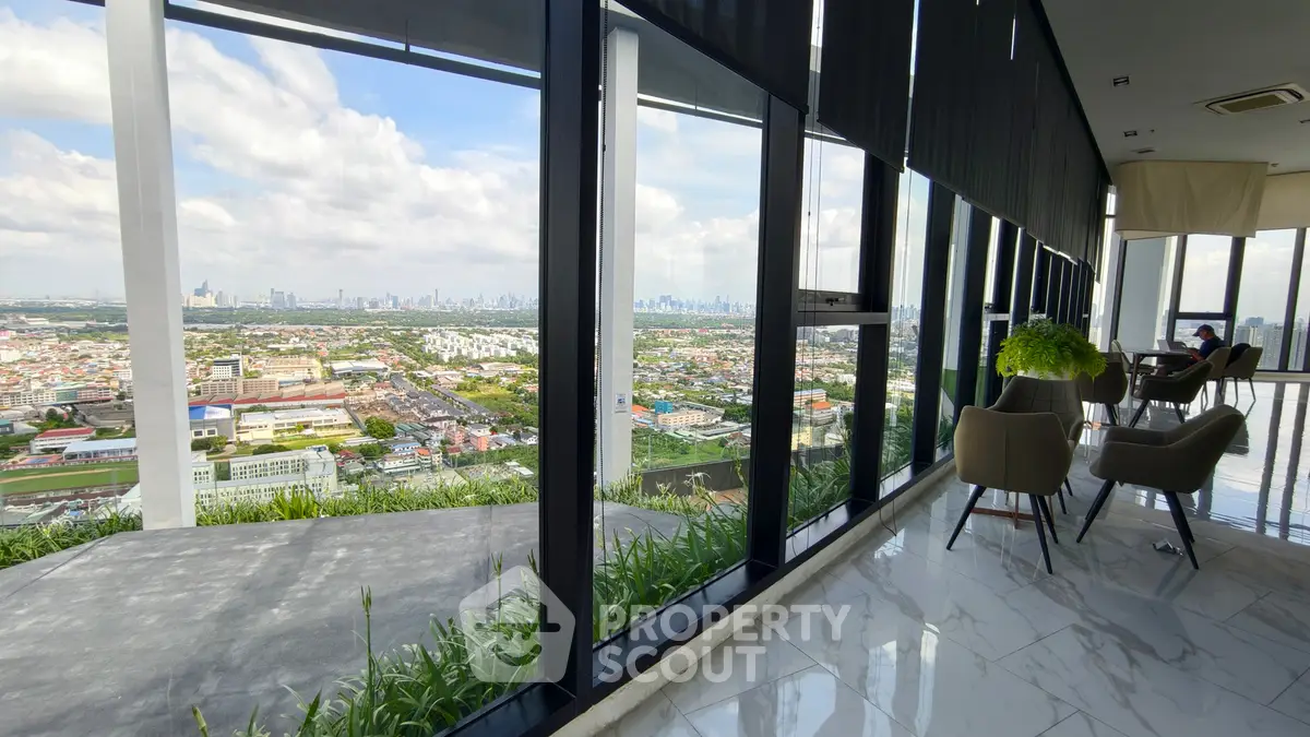 Stunning high-rise view from modern building with floor-to-ceiling windows and elegant interior seating area.