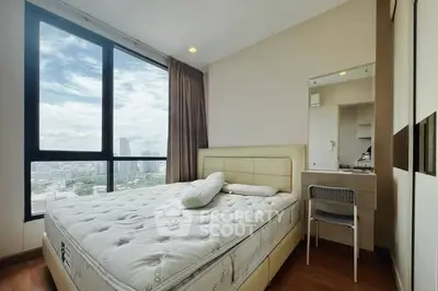 Spacious bedroom with city view and modern furnishings in high-rise apartment.