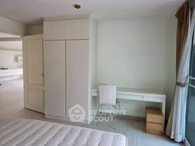 Spacious bedroom with modern furniture and large window for natural light.