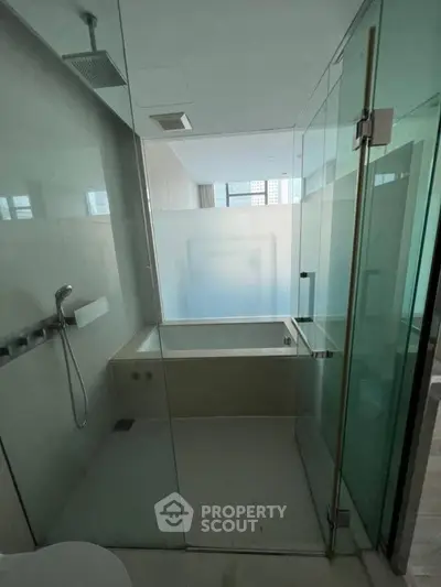 Luxurious modern bathroom with glass shower and bathtub in high-end apartment.
