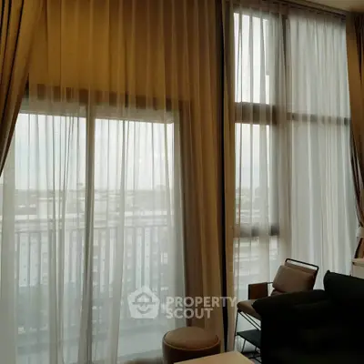 Spacious living room with floor-to-ceiling windows and elegant curtains