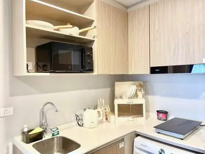 Modern kitchen with sleek cabinetry and appliances, featuring a microwave and washing machine.