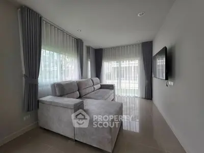 Modern living room with sleek gray sofa and large windows