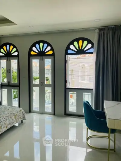 Elegant bedroom with arched windows and stylish decor, offering a bright and inviting atmosphere.