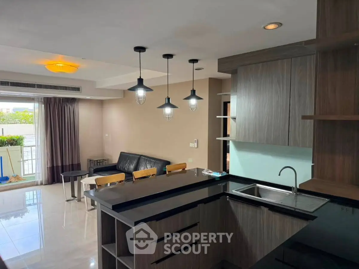 Modern open-layout kitchen and living room with stylish lighting and balcony view.