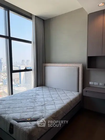 Modern bedroom with city view, featuring a stylish bed and large window for natural light.