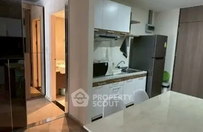 Modern kitchen with sleek cabinetry and dining area in cozy apartment