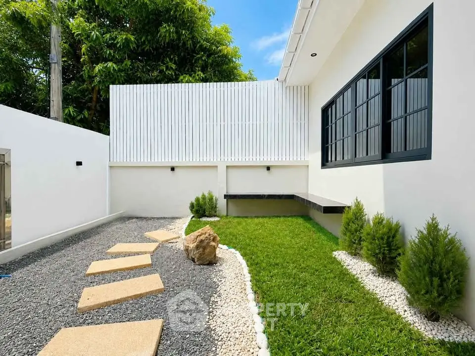 Modern minimalist garden with stepping stones and lush greenery in a contemporary home exterior.