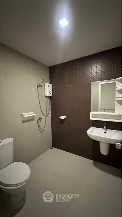 Modern bathroom with sleek fixtures and neutral tiles, featuring a shower and wall-mounted sink.