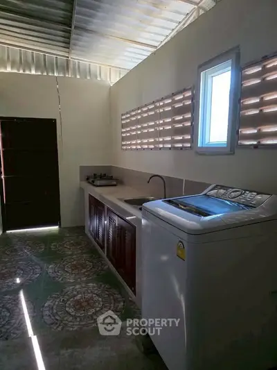 Compact kitchen with washing machine and gas stove in a cozy home setting.