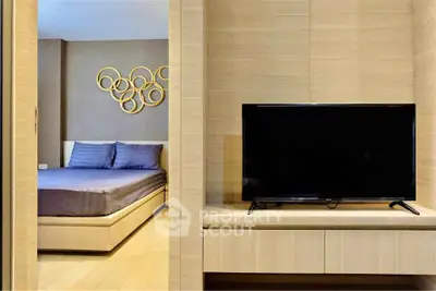Modern bedroom with stylish decor and flat-screen TV in a cozy apartment.