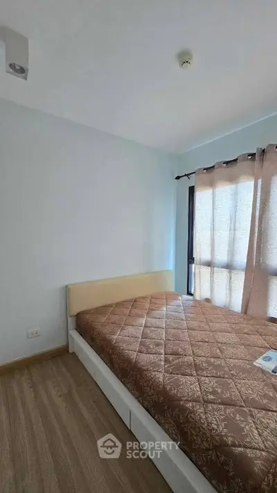 Cozy bedroom with natural light and minimalist design, featuring a comfortable bed and wooden flooring.