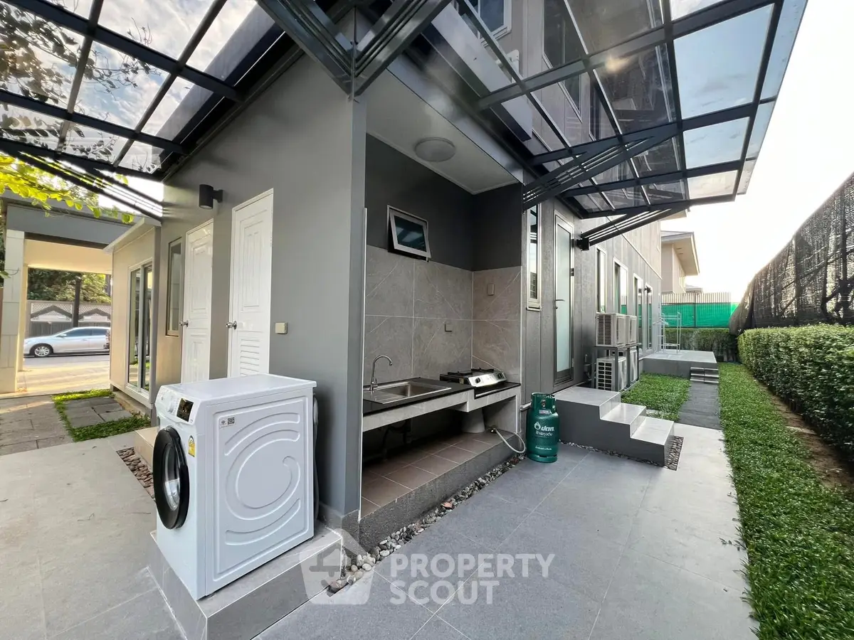 Modern outdoor laundry area with washing machine and sink in stylish residential property.