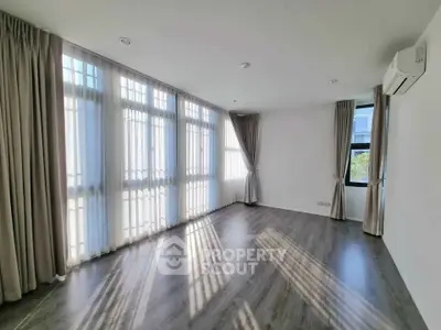 Spacious sunlit room with elegant curtains and modern flooring, perfect for a stylish living area.