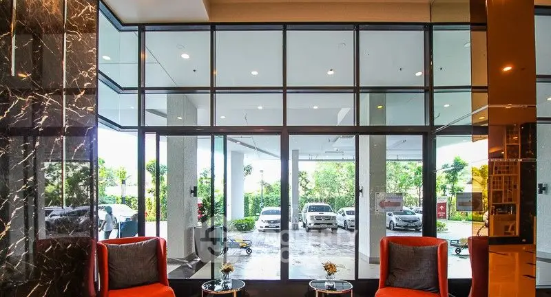 Luxurious building entrance with modern glass facade and stylish seating area.