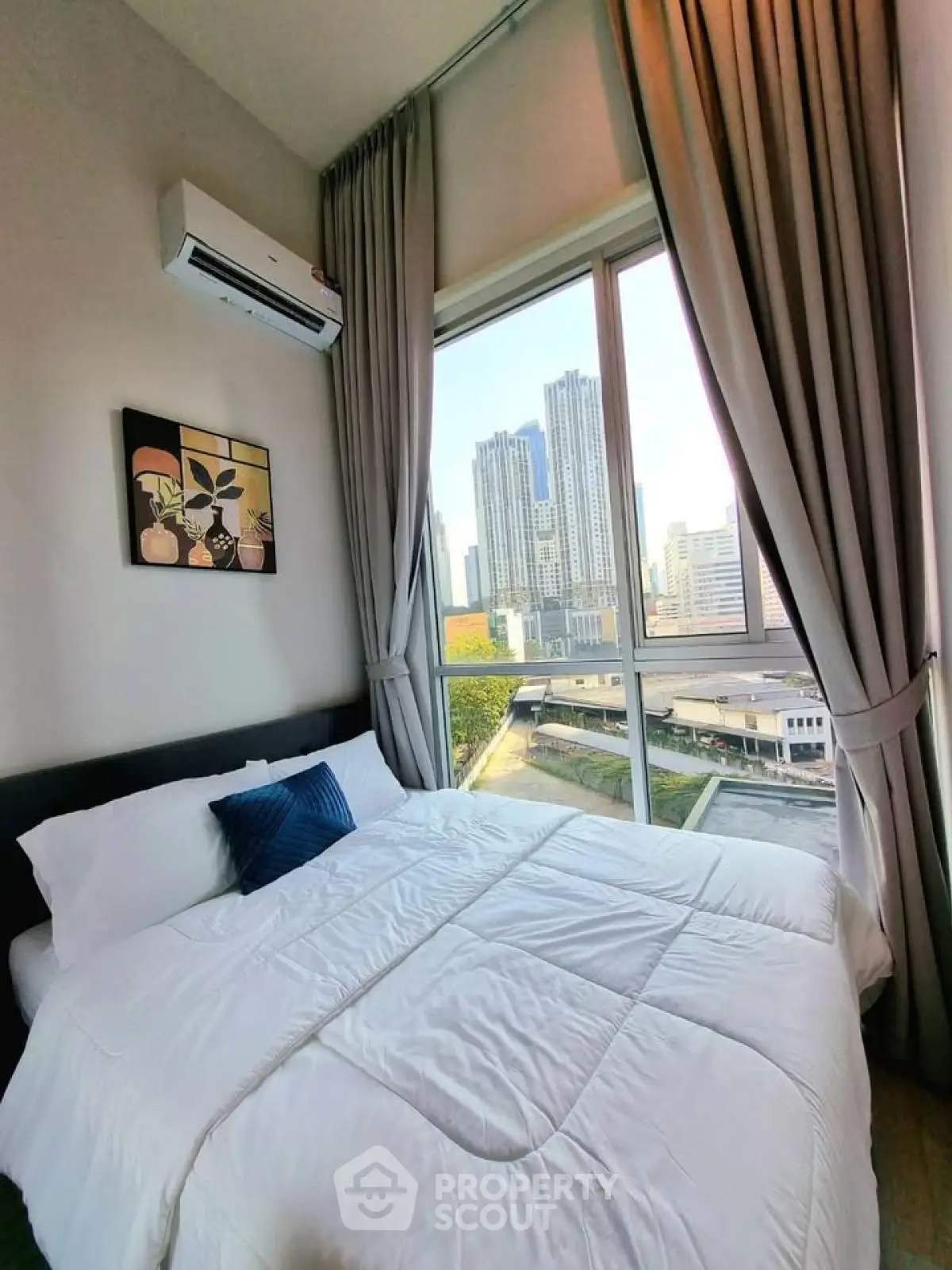 Modern bedroom with city view and large window, featuring elegant decor and natural light.