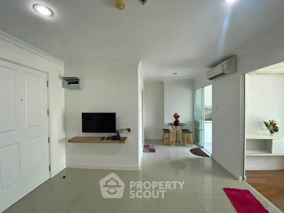Modern living room with sleek TV setup and open layout, featuring bright tiles and contemporary decor.