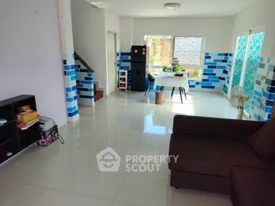 Spacious living room with modern decor and natural light, featuring a cozy sofa and stylish blue accents.