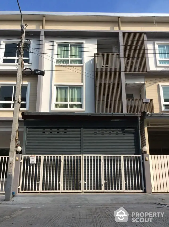 Modern townhouse with a secure roller shutter garage door, featuring a stylish facade and large windows for ample natural light.