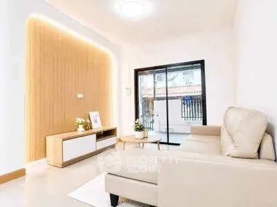Modern living room with beige sofa and sliding glass doors leading to a balcony.