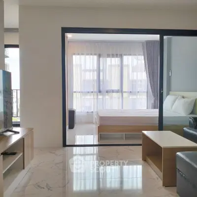 Modern apartment interior with open living room and bedroom, featuring sleek furniture and large windows.