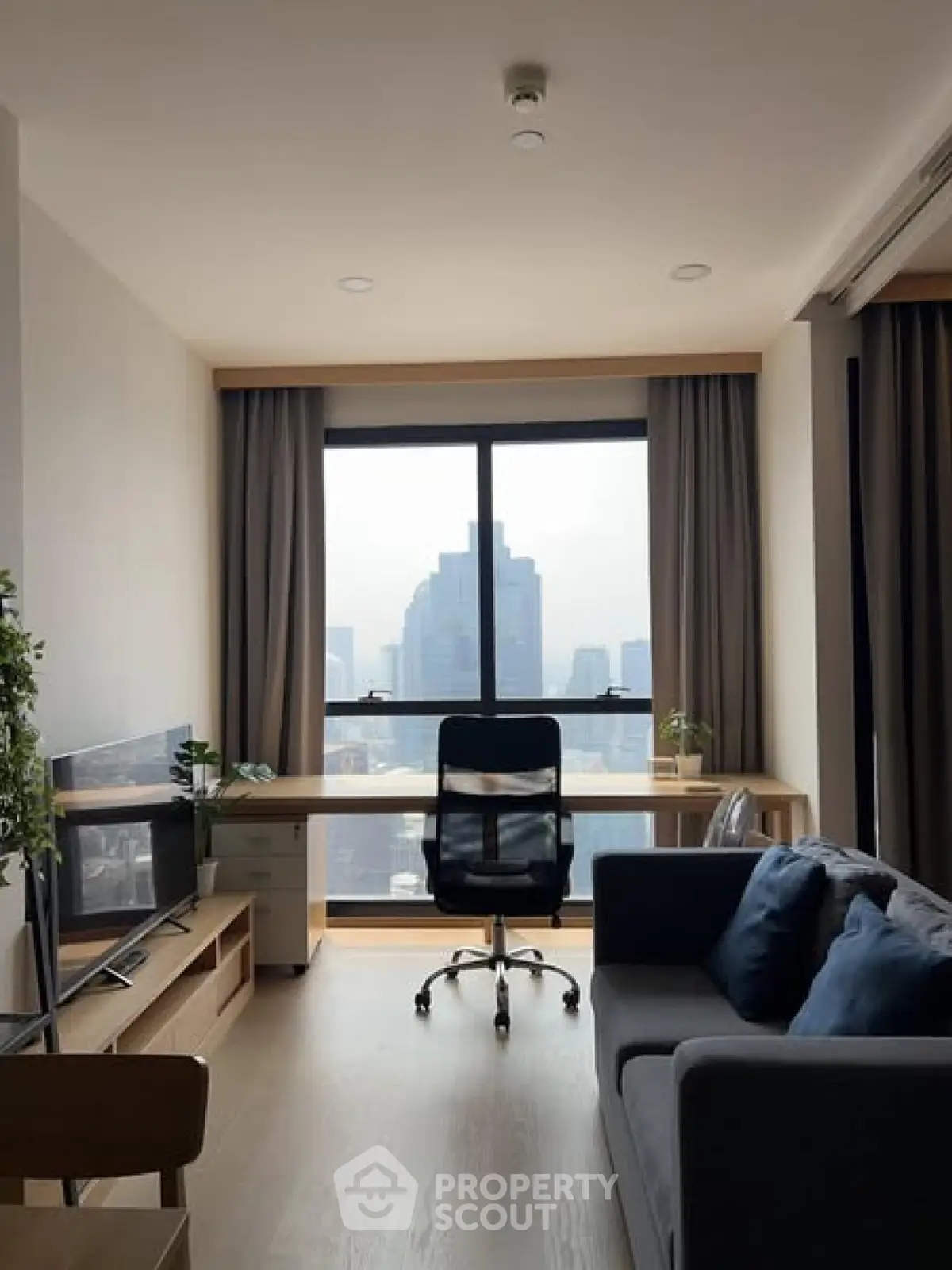 Modern living room with city view, featuring sleek furniture and large window.