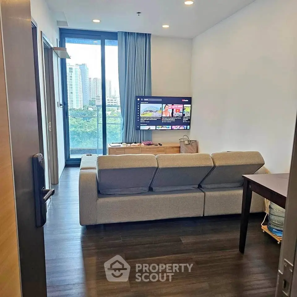 Modern living room with city view, featuring sleek furniture and large windows for natural light.
