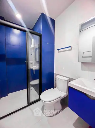 Modern bathroom with blue accents and glass shower enclosure