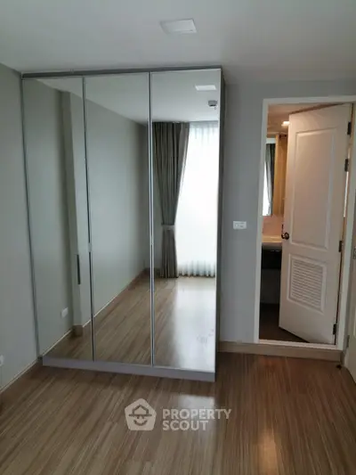 Spacious bedroom with mirrored wardrobe and ensuite bathroom in modern apartment.