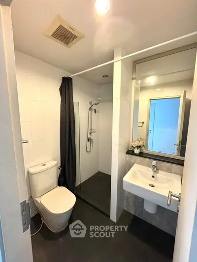 Modern bathroom with sleek design, featuring a glass shower enclosure and contemporary fixtures.