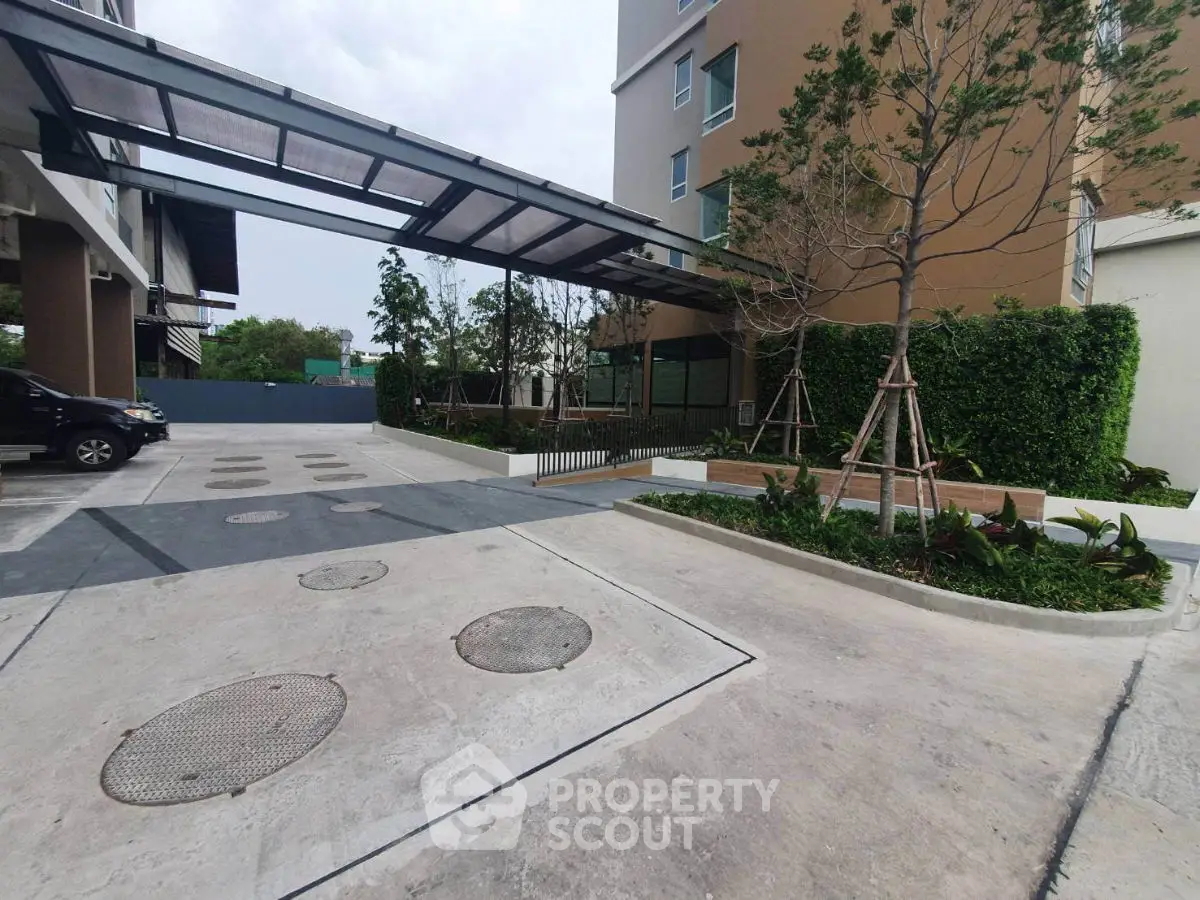 Modern building entrance with landscaped garden and covered driveway