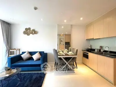 Modern open-plan living space with a sleek kitchen, dining area, and cozy lounge, featuring stylish furnishings and ample natural light.