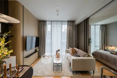 Modern living room with cozy sofa and large TV, open to elegant bedroom