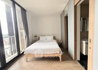 Modern bedroom with large windows and balcony access in a high-rise apartment.