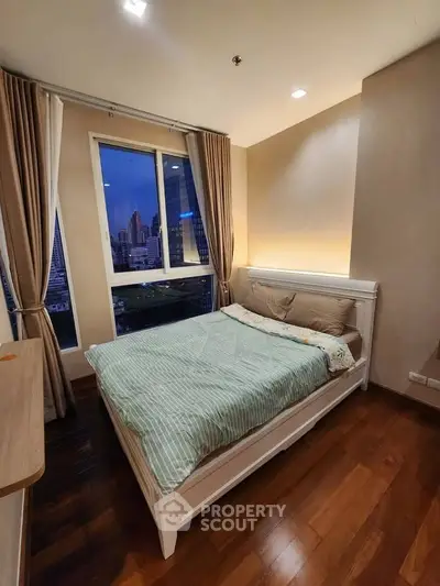 Cozy bedroom with city view, wooden flooring, and elegant curtains in modern apartment.