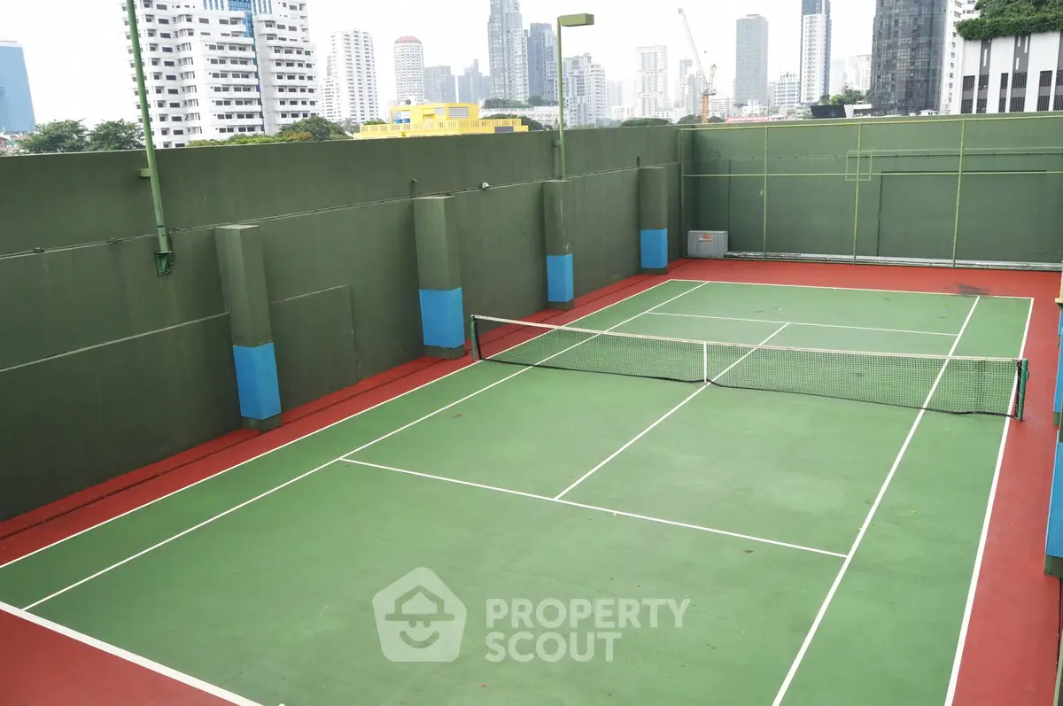 Spacious rooftop tennis court with city skyline view, perfect for sports enthusiasts seeking urban living.