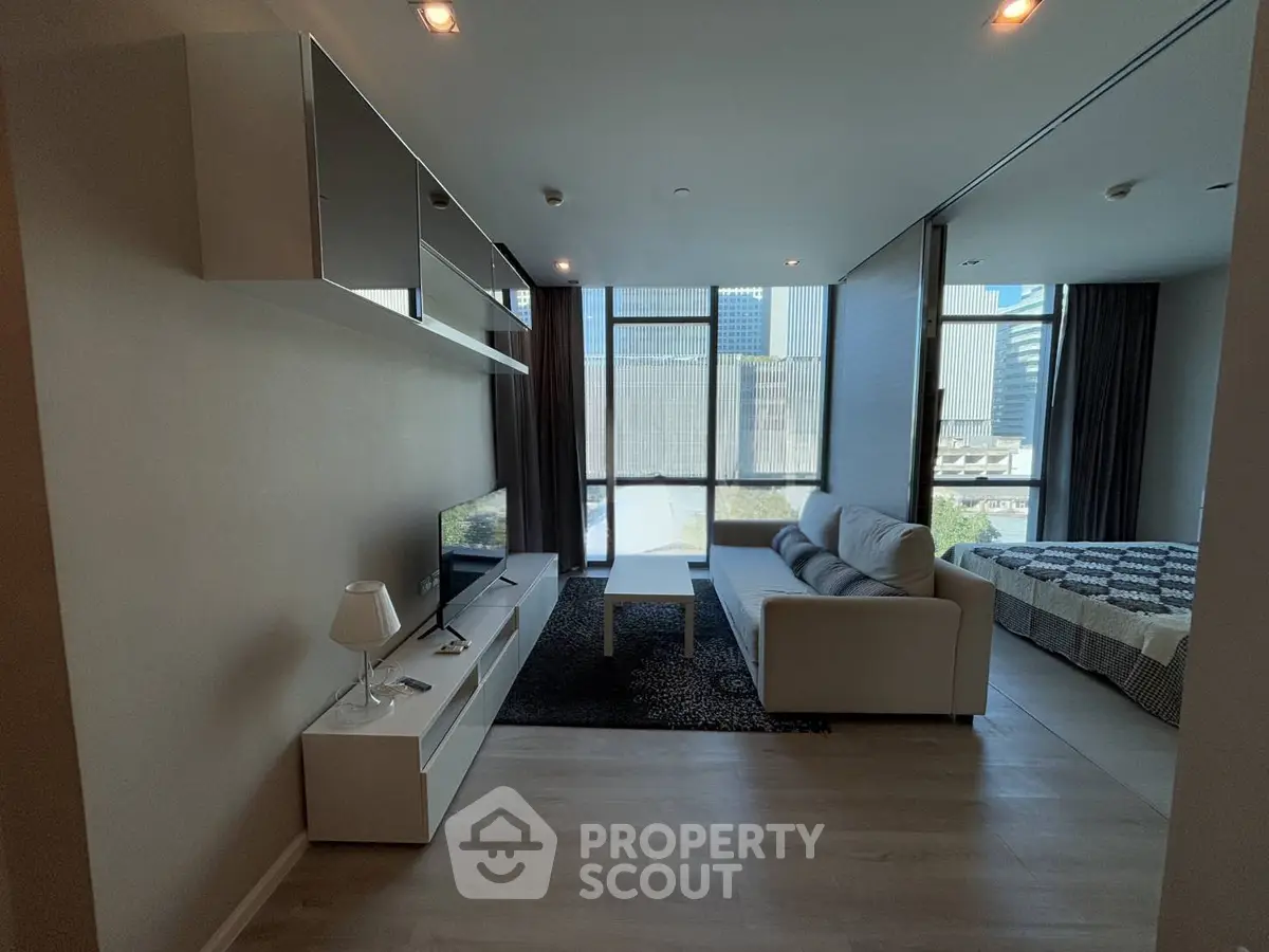 Modern living room with sleek furniture and large windows offering city views